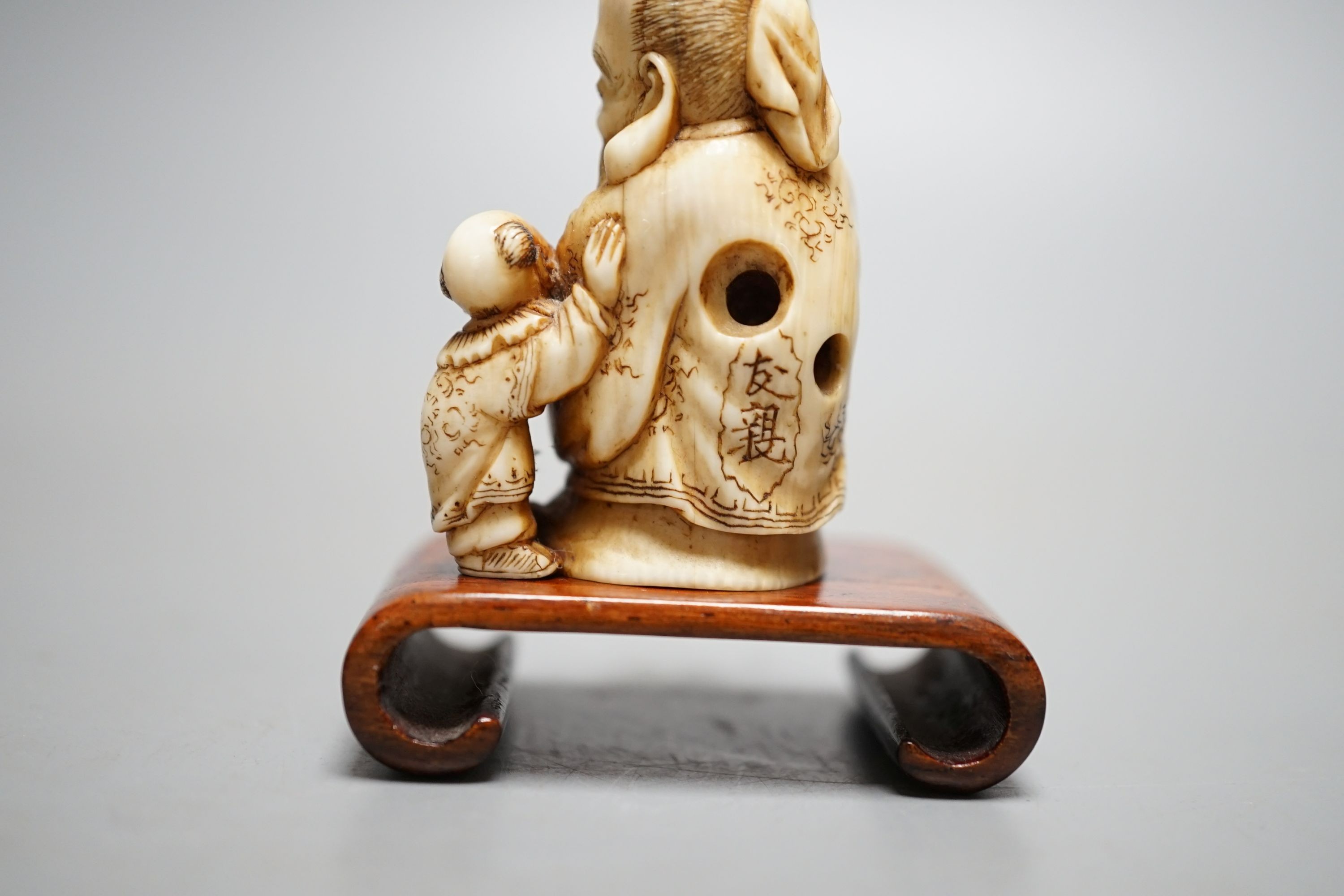 A Japanese ivory netsuke of Hotei and a boy, Meiji period, signed, 5 cms high.